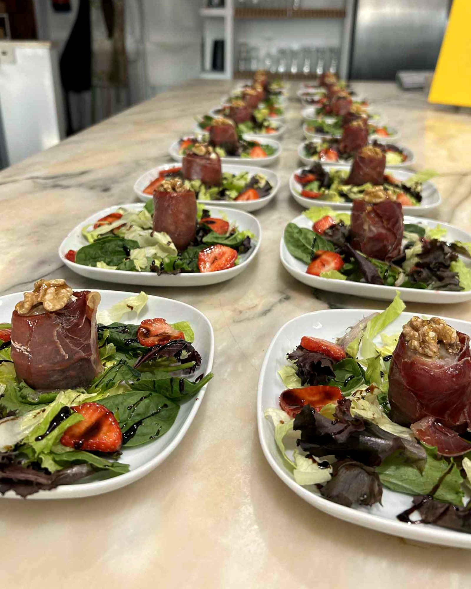 A run of plated jamón and walnut starters ready for service at a villa dinner cooked by Simon
