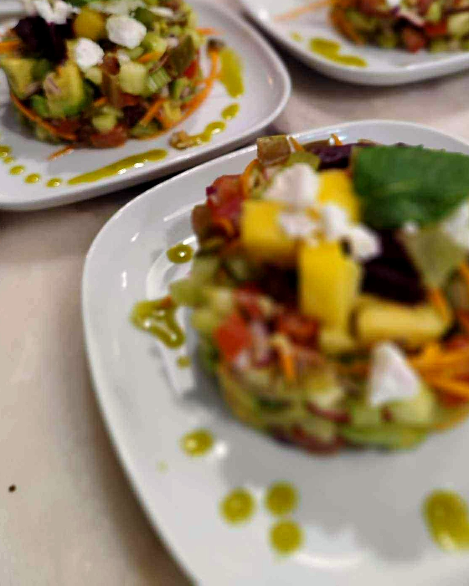 Vegetable tartare starters with mango, goat's cheese and herb oil, plated for a villa dinner
