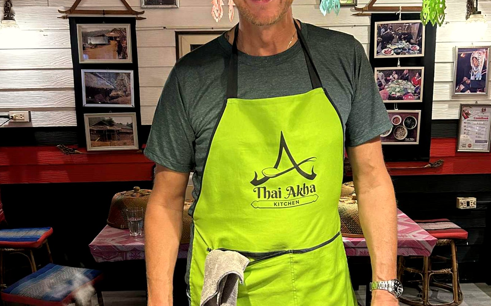 Simon cooking at a kitchen counter, apron on, pan on the hob