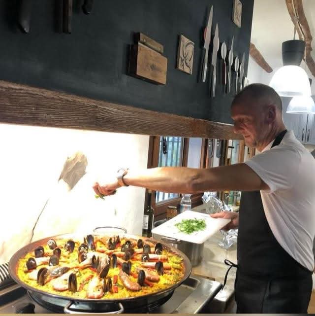 Simon finishing a seafood paella with fresh herbs in his kitchen in Spain